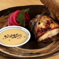 Yuzu Mizo Marinated Black Cod · Wrapped in a Japanese magnolia leaf, served with pickled red onion and yuzu miso sauce on th...