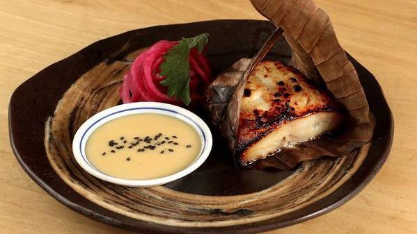 Yuzu Mizo Marinated Black Cod · Wrapped in a Japanese magnolia leaf, served with pickled red onion and yuzu miso sauce on the side.