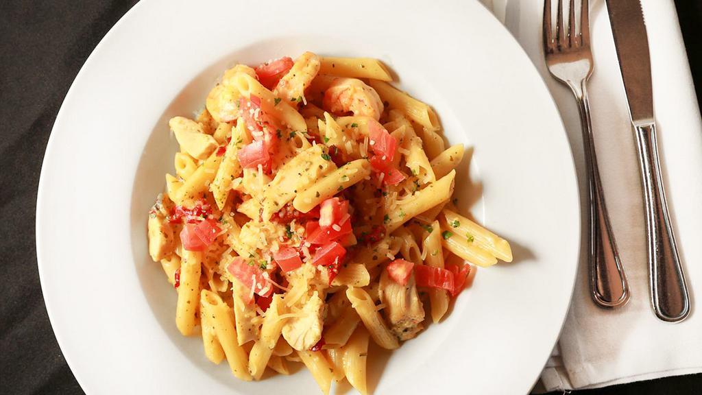 Pasta Sienna · Prawns & chicken, sautéed in extra virgin olive oil, pesto, garlic, red chili flakes, sun-dried tomatoes & penne. Tossed in alfredo, with a hint of curry, topped with fresh tomatoes & parmesan cheese.