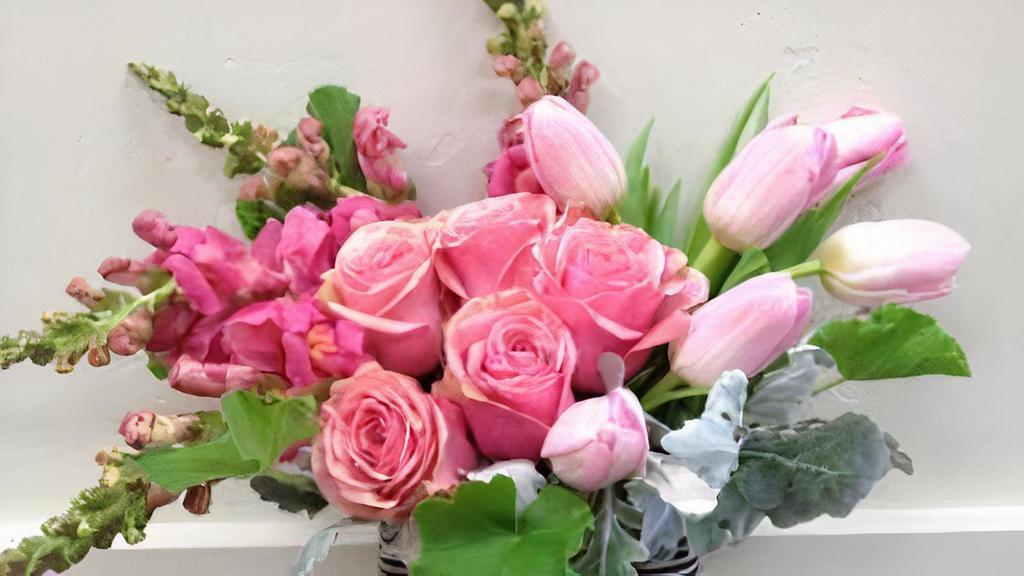 Chic Pink · The Chic Pink arrangement will bring a bright smile to one's face.  Featuring roses,  tulips and snapdragons and accented with dusty miller and finished off with a chic black and white striped ribbon.
