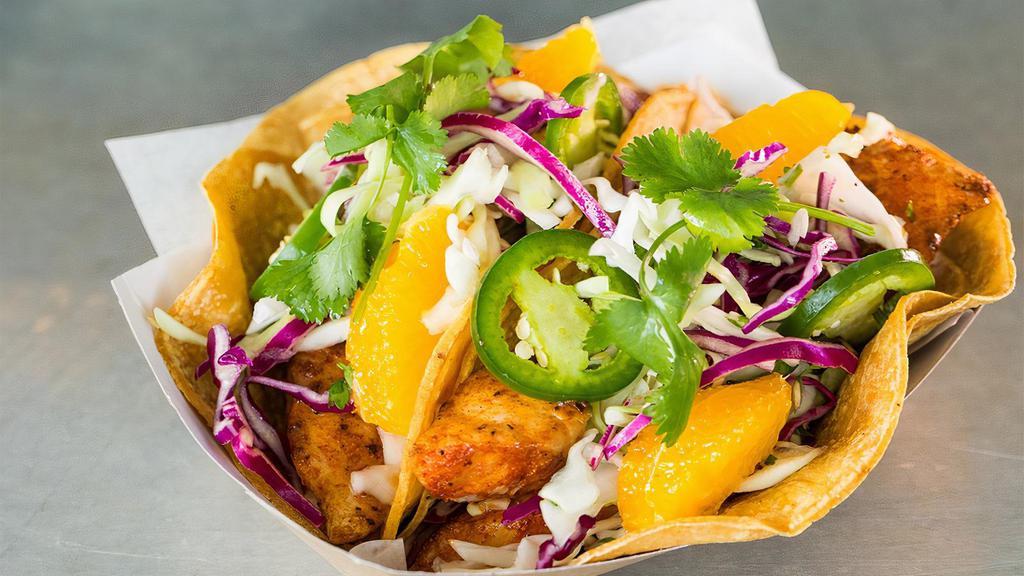 Mahi Mahi Tacos · Fresh mahi mahi* with spicy Asado seasoning, griddled and served in soft organic corn tortillas with green cabbage & cilantro slaw, cilantro, jalapeño, oranges & crema. 2 tacos per order.. *Due to seasonal availability, fresh, wild caught halibut may be substituted.