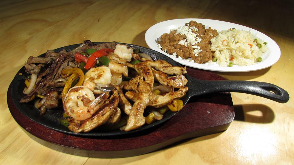 Fajitas Trio · Delicious slightly spiced strips of meat, chicken & shrimp, sauteed with red and green bell peppers, and onions, served with salad, rice beans, cheese,  and sour cream.