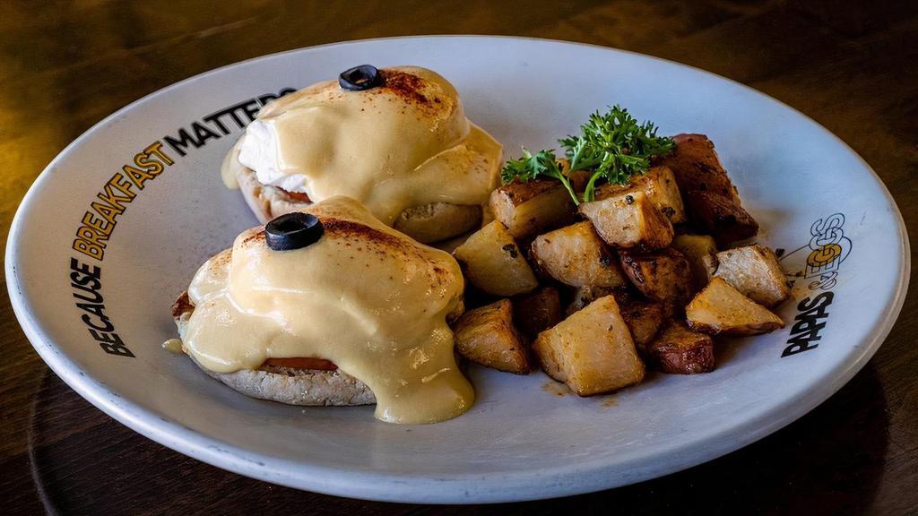 Eggs Benedict Canadian-bacon · Benedict with Canadian-bacon. English muffin topped with poached eggs, smothered with hollandaise sauce, served with roasted potatoes.