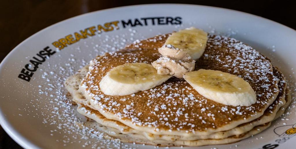 Banana Pancakes · Our buttermilk premium pancakes filled with diced fresh bananas, served with whipped butter and hot tropical syrup, Dusted with powdered sugar.