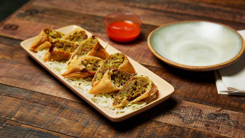 Burmese Samusas · Four handmade pastries filled with curried potatoes, mint and masala spices. Stuffed with green peas, chicken or lamb. Crispy on the outside and soft on the inside, served with our spicy and tangy house red sauce.