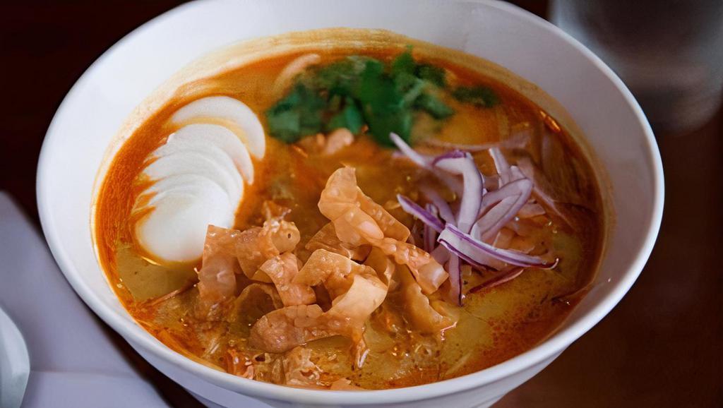 Coconut Noodle Soup · Creamy coconut milk soup served with chicken, egg noodles, hard-boiled egg, cilantros, fresh red onions and wonton chips.