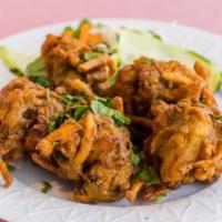 Onion Pakoras · Thinly sliced onion dipped in mildly spiced garbanzo bean (chickpea flour) batter and fried.