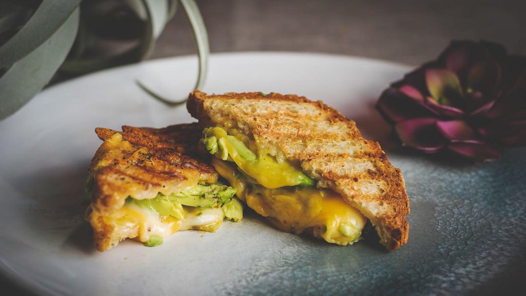Avocado Grilled Cheese · Gluten-free bread, mayo, organic cheddar cheese, organic pepper jack cheese, pickled carrots, and avocado. Served with green sauce on the side.
