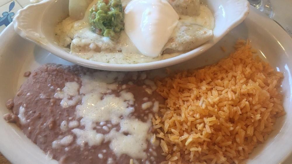 Enchiladas Puerto Vallarta · Two flour tortillas filled with tender prawns, onions, mushrooms and peppers. Lightly seasoned, covered with tomatillo sauce and cheese. Topped with sour cream and guacamole. Served with rice and beans.