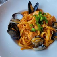 Seafood Fettuccine · Salmon, shrimp, clams mussels, and green onions in a light creamy pomodoro sauce.