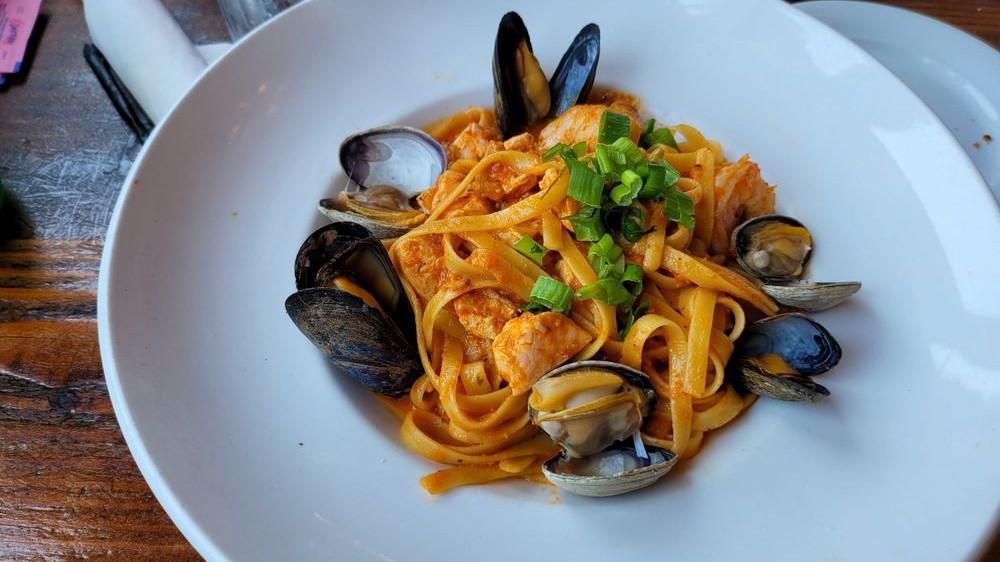 Seafood Fettuccine · Salmon, shrimp, clams mussels, and green onions in a light creamy pomodoro sauce.