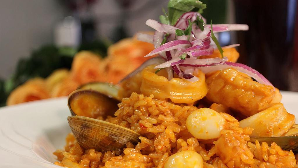 Arroz Con Mariscos · Fried rice with ají panca, wine, sautéed mussels, calamari, red onions, tomatoes & corn, topped with salsa criolla.