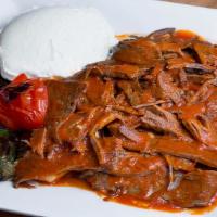 Iskender Kebab Plate · Lamb and beef doner thinly sliced on pita bread pieces with yogurt and tomato sauce.