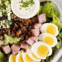 Protein Cobb Salad · 979 cal. Lettuce, fanned avocado, hard-boiled egg, crispy bacon, diced ham, crumbled bleu, w...