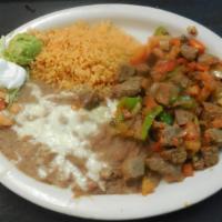 Carne Guisada · Steak cutlers grilled with onions, bell peppers, tomatoes and spices. Served with rice, bean...