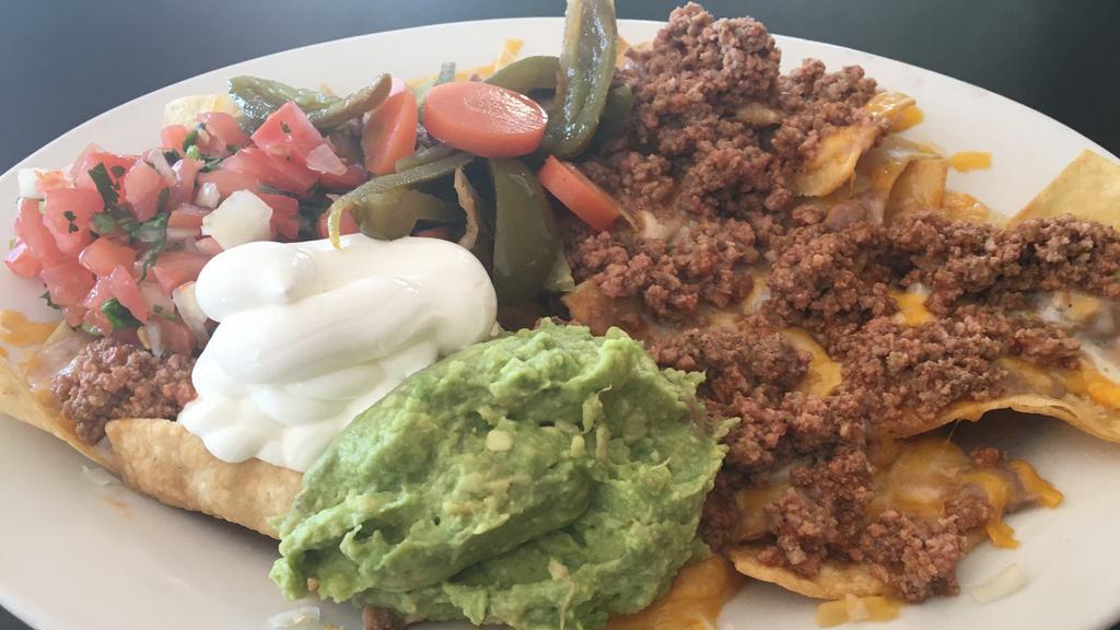 Azteca Nachos · Fresh corn tortilla chips topped with ground beef, refried beans, melted monterey jack, cheddar cheese, homemade guacamole, sour cream and pico de gallo.