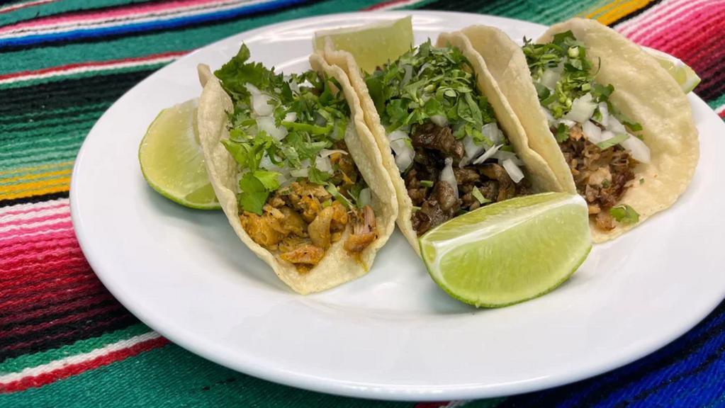 Taco Plate · Two tacos on homemade tortillas top with cilantro and onions a side of rice and beans.