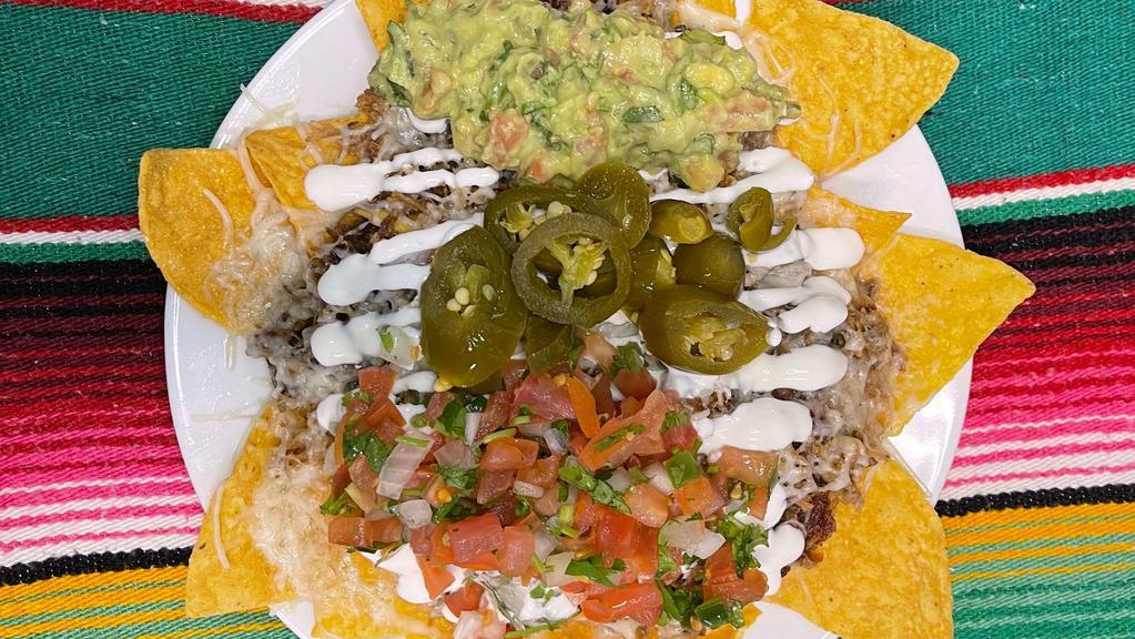 Super Nachos · Homemade tortilla chips, choice of meat, refried beans, cheese, guacamole, sour cream, jalapeños, and pico de gallo.
