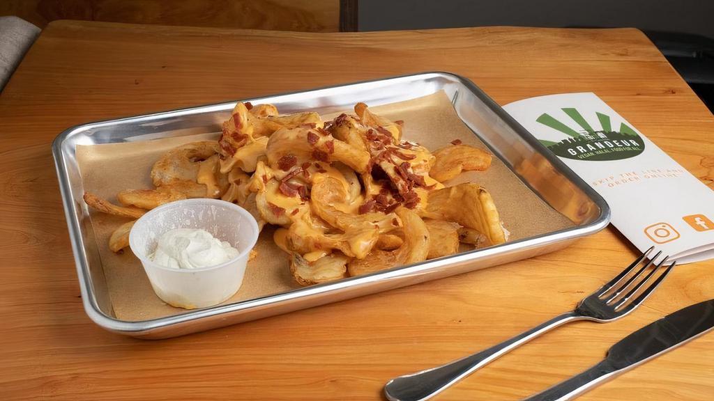 Twisted Town Fries · Our signature curly wedge fries covered in melted cheddar cheese, topped w/bacon bits & grilled onions.