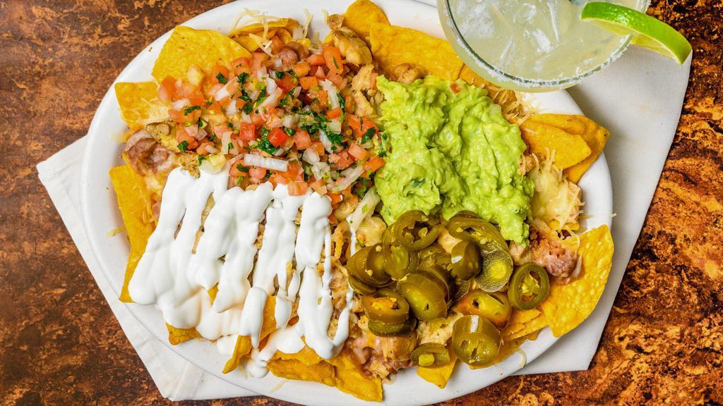Nachos · Tortilla chips topped with refried beans, Monterey Jack cheese, guacamole, sour cream, fresh pico de gallo, jalapeño, and your choice of meat.