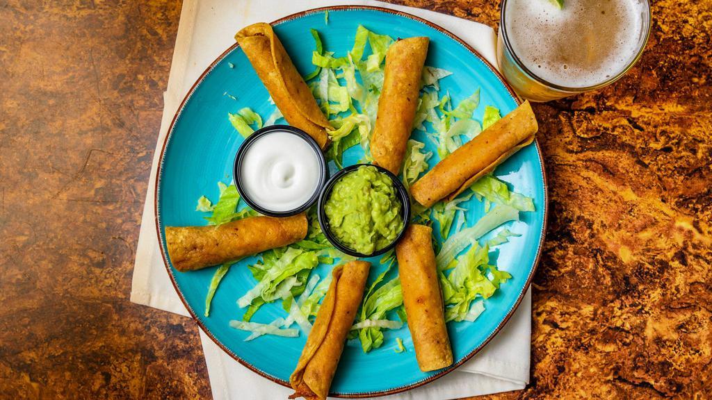 Taquitos (6) · Chicken taquitos served on a bed of lettuce, sour cream, and guacamole.