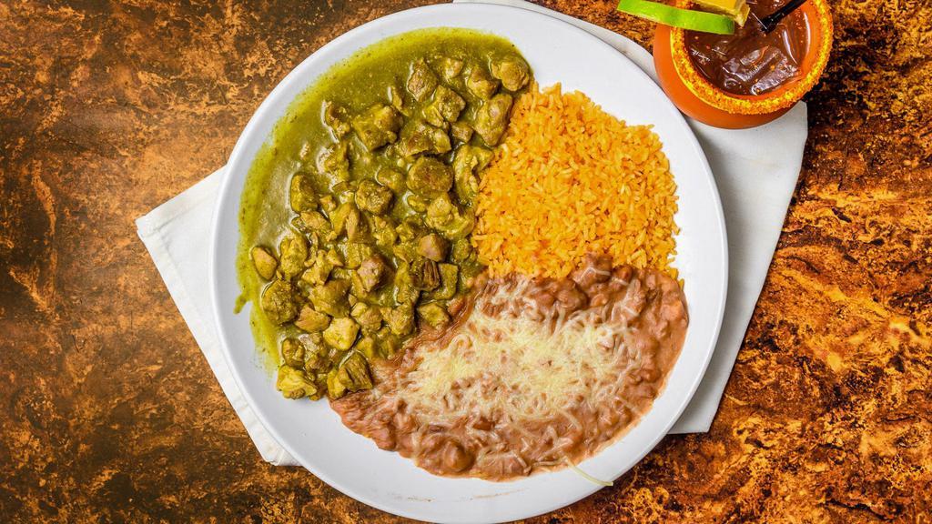 Chile Verde · Tender pieces of pork simmered in a mild green sauce. Served with rice, refried beans topped with cheese, and a side of tortillas.