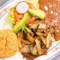 Bistec Encebollado · Thinly sliced steak and sauteed onions. Served with rice, beans, guacamole and corn tortillas.