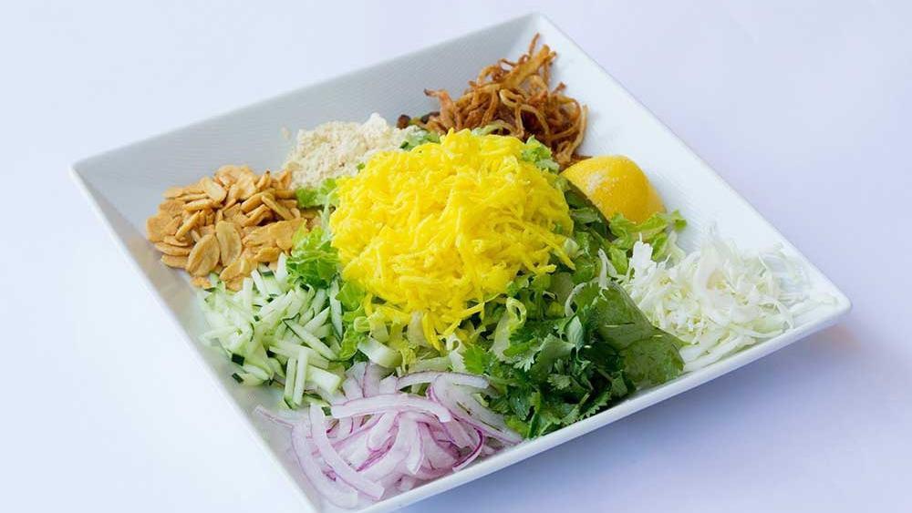 Mango Salad · Shredded fresh green mangoes served with fried onions, fried garlic, cabbage, red onions, yellow bean powder, cucumber, cilantro, and dried shrimp.