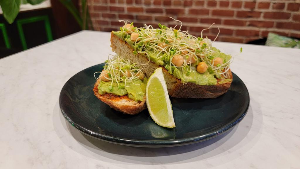 Avocado Toast · Vegan. Whole grain levain, avocado, Moroccan style harissa (mildly spicey), house pickled onions, chickpea, sprouts, lime wedge.