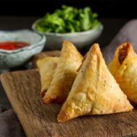 Samosa Chili · Crispy, savory pastry with potatoes, peas, fresh bell peppers, and onions. Served with a dem...