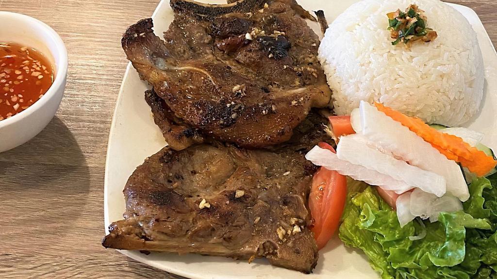 Cơm Sườn · Grilled pork chop with steamed rice and vegetables.