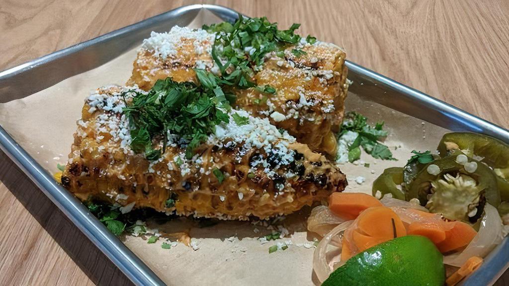 GRILLED ELOTE · One whole ear of Mexican grilled street corn smothered in chipotle aioli, cilantro, and cotija cheese.