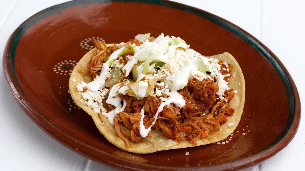 Tostada · Crispy corn tortilla, topped with chicken, onions, lettuce, salsa, cheese and cream.