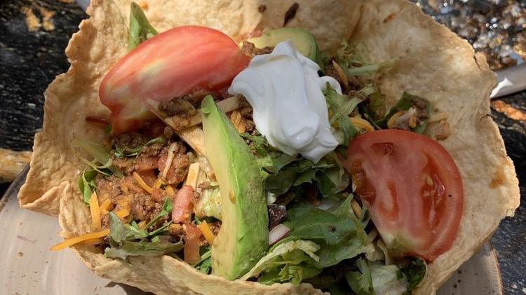 TACO SALAD  Ground Beef · In a crispy tortilla shell with chicken ranchero or shredded beef, lettuce and warmblack beans. Topped with cheese, salsa fresca, avocado, tomatoes and sour cream.