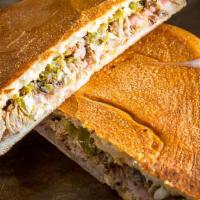 Mexican Torta Cubana · Slow cooked pork carnitas, ham, cheese, refried beans, avocado, pickles, and Habanero mayo