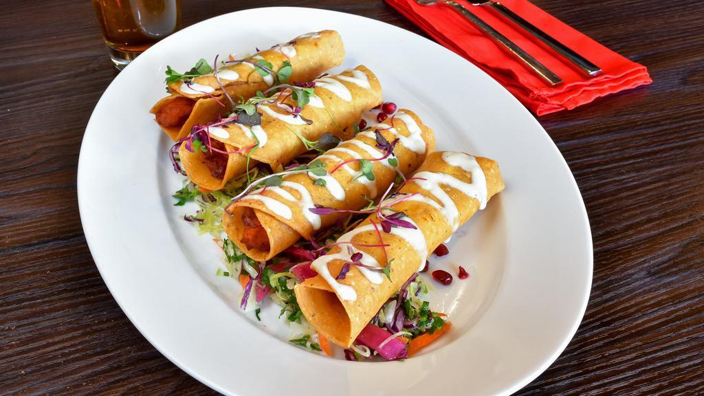 Flautas de Camote · Vegan. Sweet potatoes flautas garnished with cream of almond, Mexican coleslaw, pomegranate & pickled onions.