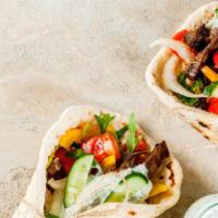 Lamb Shawarma Wrap · Classic lamb shawarma wrap tossed with grilled onions, tomatoes, and garlic sauce. Served wi...