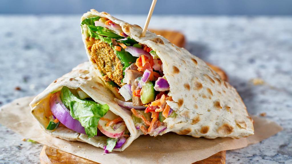 The Falafel Wrap · Crispy chickpeas wrapped in pita bread with lettuce, tomatoes, onions, parsley, pickles, cucumbers, hummus and tahini sauce.