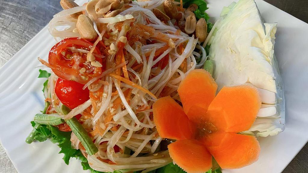A03. Papaya Salad · Shredded green papaya with tomatoes, green bean, ground peanut, dry shrimps in spicy lime dressing served with sliced cabbage.