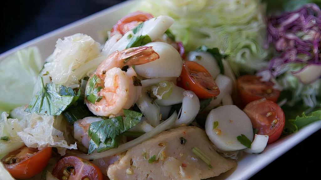 A01. Spicy Seafood Salad · Shrimps, calamari, fish balls, scallops, white fungus and sliced fish cakes with tomatoes, onion in the spicy lime dressing served with sliced cabbage.