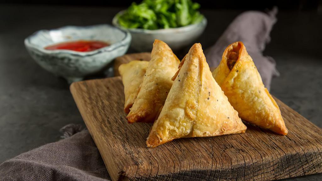 Crispy Samosas · Crispy pastries filled with potatoes, peas, and ginger-garlic. Served with mint and tamarind chutney!