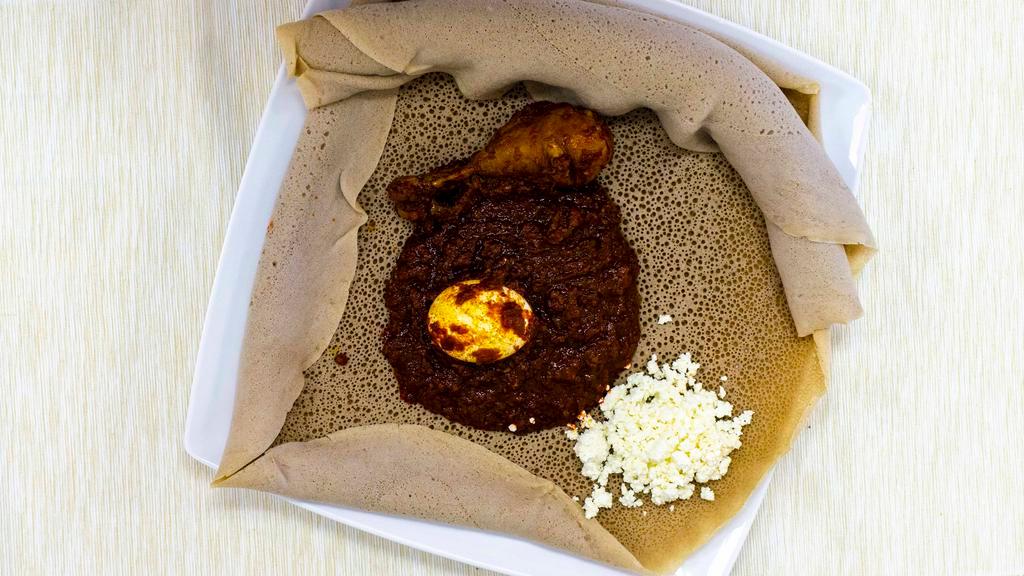 Doro Wot · Spicy Ethiopian chicken stew - cooked with onion, garlic, ginger, berbere, Ethiopian spiced butter, hard bowling egg. Serve with injera (flat bread), homemade chees.