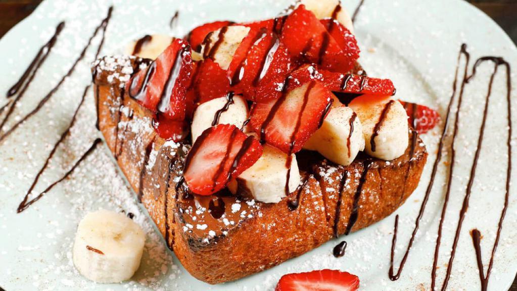 Fruity Choco Nutella Toast · Toasted brick styled bread topped with a spread of nutella, slices of banana & strawberry, sprinkled in white sugar powder and drizzled honey.