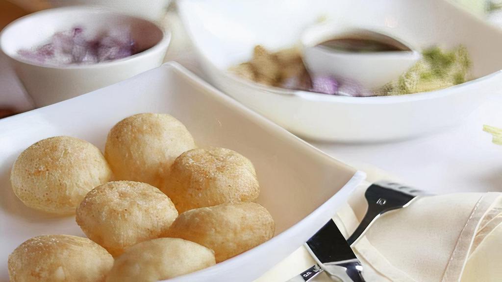 Pani Poori · Crispy puffed wafers served with spicy mint water, chutneys, potatoes, onion, sprouts, and chickpeas.