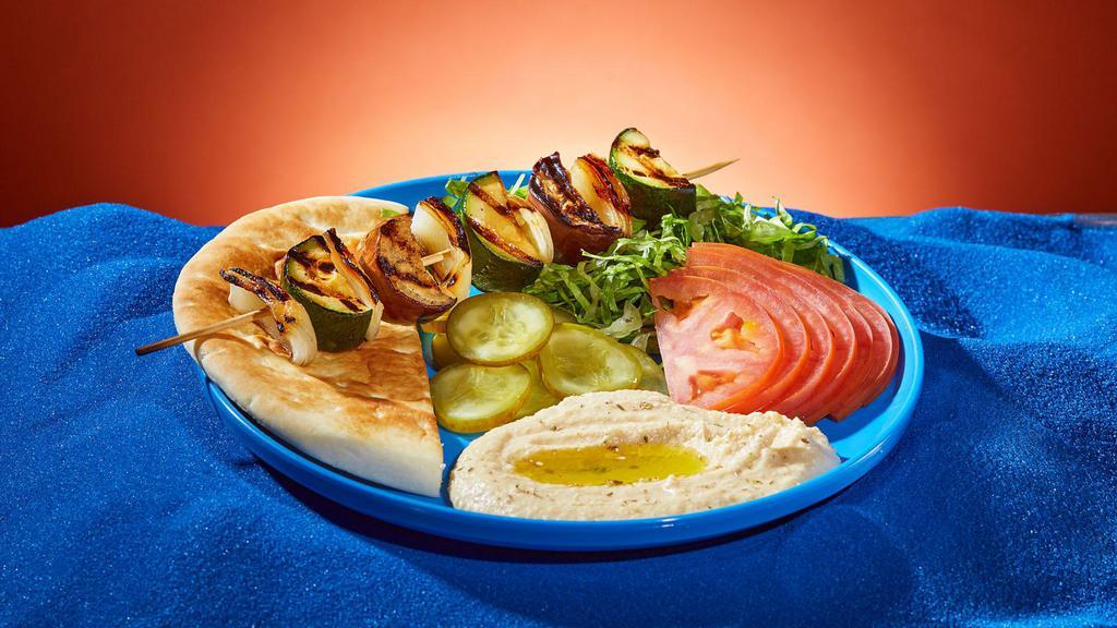 Grilled Veggie Kebab Platter · Onions, zucchini, and eggplant grilled on a skewer. Served with rice or hummus, lettuce, tomato, pickles, and pita.