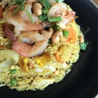 Pineapple Fried Rice · Eggs, pineapples, carrots, peas, onions, tomatoes, cashew nuts, and raisins with yellow curr...