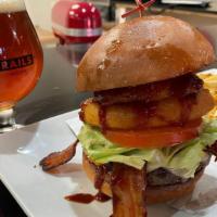 The Western Burger · White cheddar, bacon, pickles, lettuce, tomato, house made onion rings, topped with house bo...