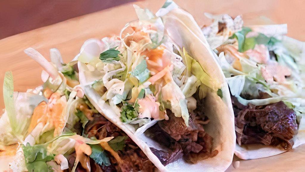 Korean Street Tacos · gojuchang marinated chicken over shredded lettuce and topped with picked daikon, ginger and green onions