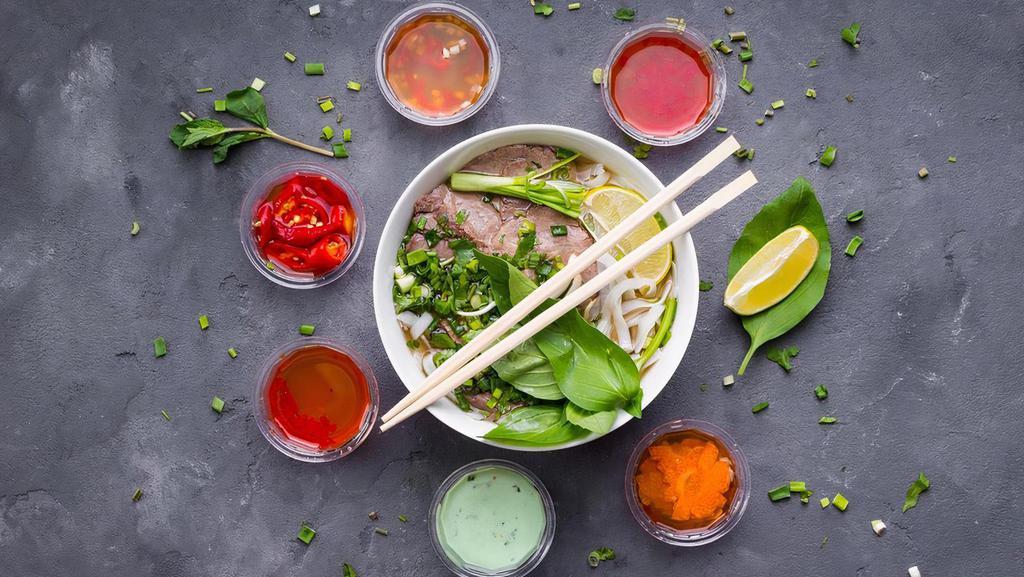 Pho Bo (Beef) · Beef bone broth, USDA black Angus rare steak, beef brisket, and beef meat ball. Home-made, slow-cooked (10-hour!) bone broth served steamy hot in a big bowl with rice noodle, cilantro, basil, onions, lemon wedges, and bean sprout.