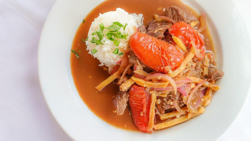 Lomo Saltado · Top sirloin strips stir fried with onions and tomatoes in a special Peruvian sauce - topped with pommes frites.